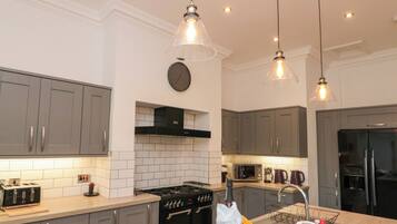 A modern kitchen with grey cabinets, a black stove, and a stainless steel refrigerator.