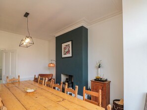 A dining room with a wooden table, chairs, a fireplace, and a hanging light fixture. - Royal Victoria House (Scarborough)