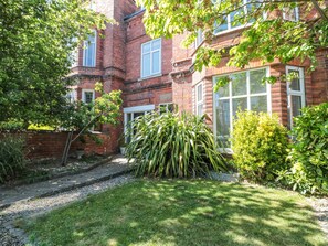 A brick building with a well-maintained garden, including a lawn and various plants. - Royal Victoria House (Scarborough)