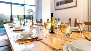 A dining table set with white plates, bowls, and wine glasses, with a bottle of wine and a framed picture on the wall. - Royal Victoria House (Scarborough)