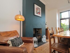 A cozy living room with a brown leather sofa, a wooden dining table, and a fireplace. - Royal Victoria House (Scarborough)