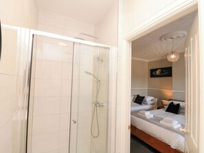 A hotel room with a shower, a bed with pillows, and a wall-mounted light fixture. - Royal Victoria House (Scarborough)