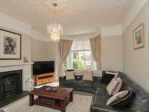 A living room with a fireplace, a television, a sofa, and a coffee table. - Royal Victoria House (Scarborough)