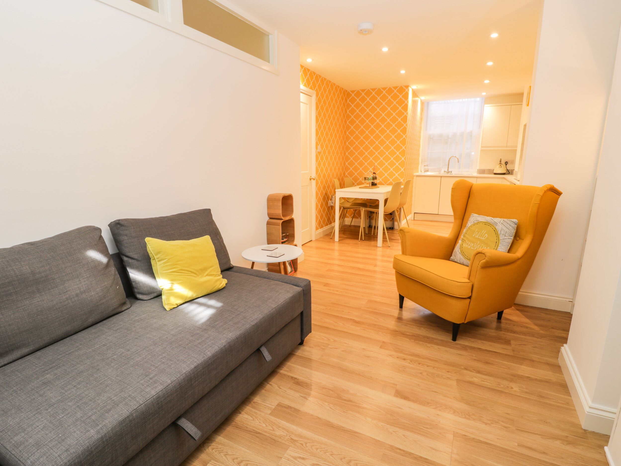 A modern living room with a grey sofa, a yellow armchair, and a small round table.