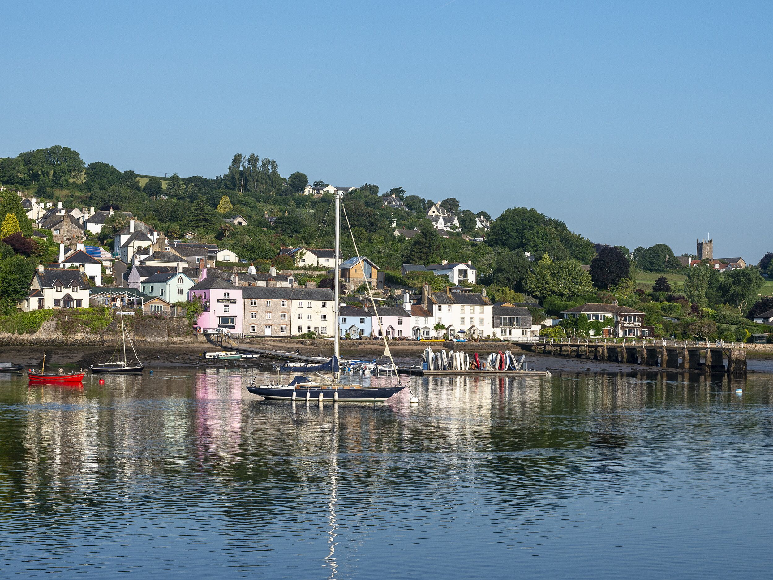 A coastal town with houses along the water, a pier, and boats.