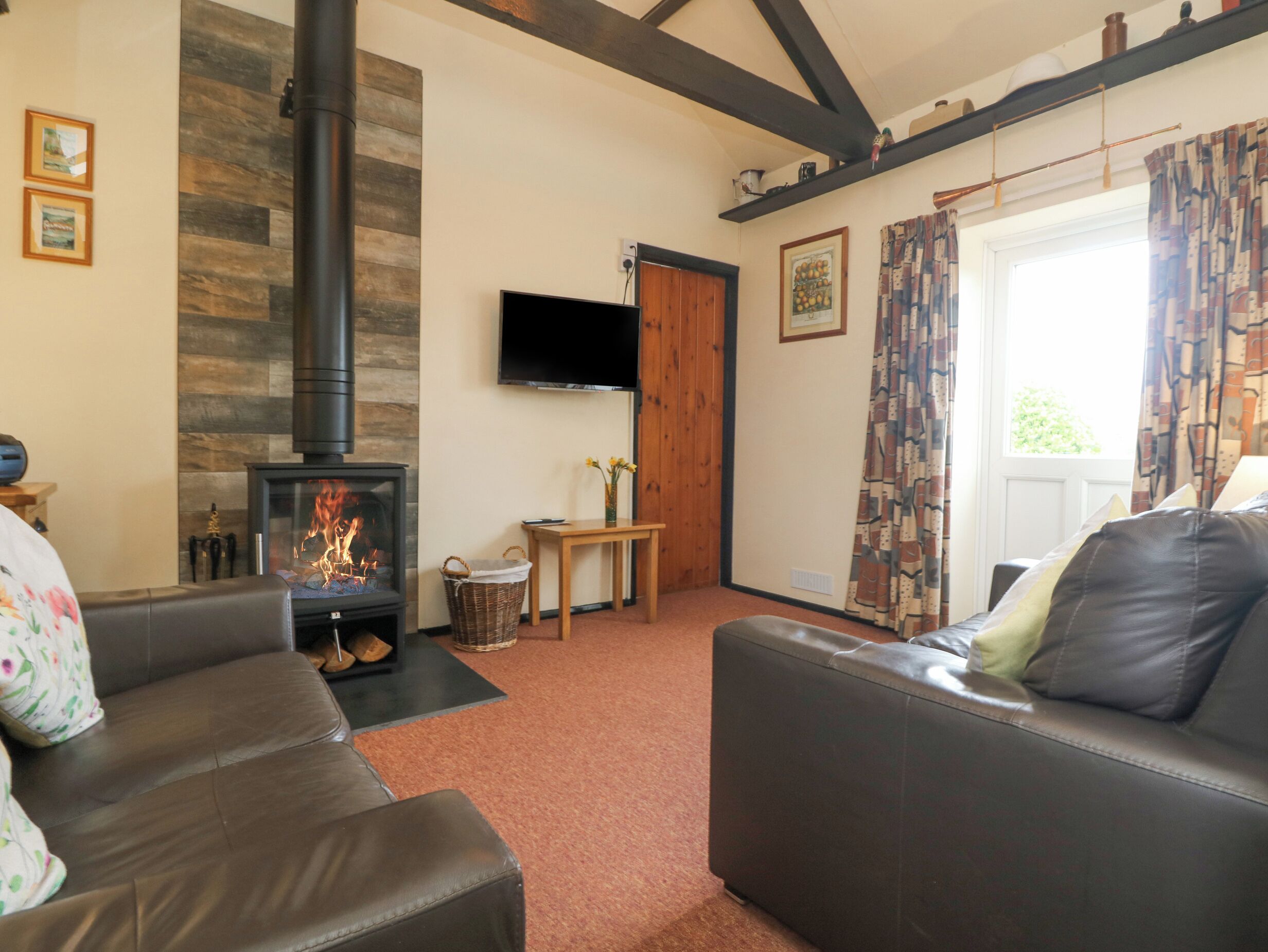 A living room with a fireplace, a sofa, a television, and a door leading outside.