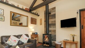 Ein Wohnzimmer mit einer Ledersofa, einem Kamin, einem an der Wand befestigten Fernseher und einem Holzregal darüber.