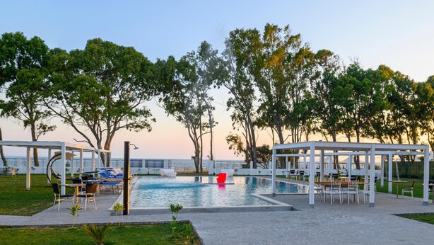 A poolside area with lounge chairs, a pergola, and a flower bed. - Hotel Lido Beach (Oristano)