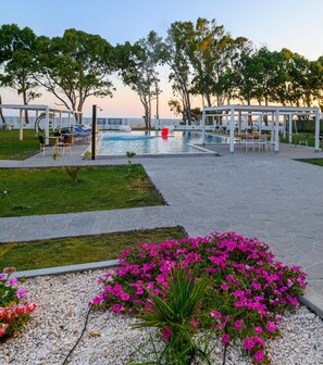 A poolside area with lounge chairs, a pergola, and a flower bed. - Hotel Lido Beach (Oristano)