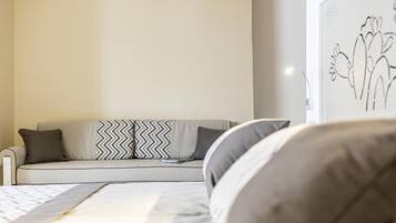 Ein Schlafzimmer mit einem Bett, einer Couch und einer Wand mit einer schlichten Linienzeichnung.