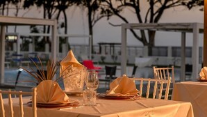 A table set for dining outdoors with a view of trees and a building in the background. - Hotel Lido Beach (Oristano)