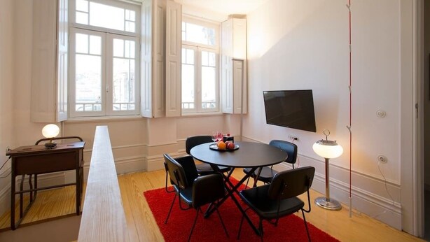 A room with a long table, chairs, a flat-screen TV, and a red rug. - 14 Esquadra  Cais das Pedras Guest House (Porto)