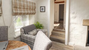 A cozy living room with a sofa, a small table, and a plant. There is a staircase leading to another room. - The Landings (Carnforth)