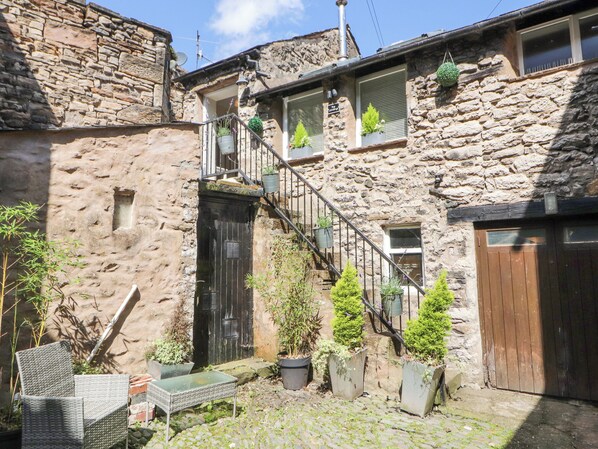 A stone building with a wooden door, potted plants, and a staircase. - The Landings (Carnforth)