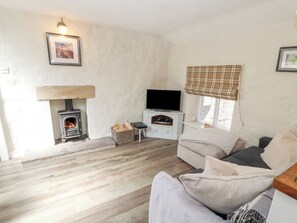 A cozy living room with a fireplace, a television, and a sofa. - The Landings (Carnforth)