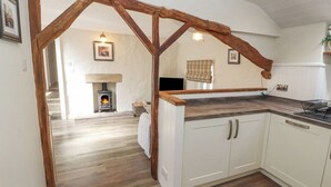 A kitchen with white cabinets, a wooden beam ceiling, and a fireplace. - The Landings (Carnforth)