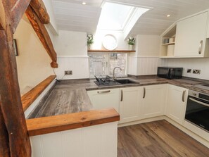 A modern kitchen with a skylight, white cabinetry, and a wooden countertop. - The Landings (Carnforth)