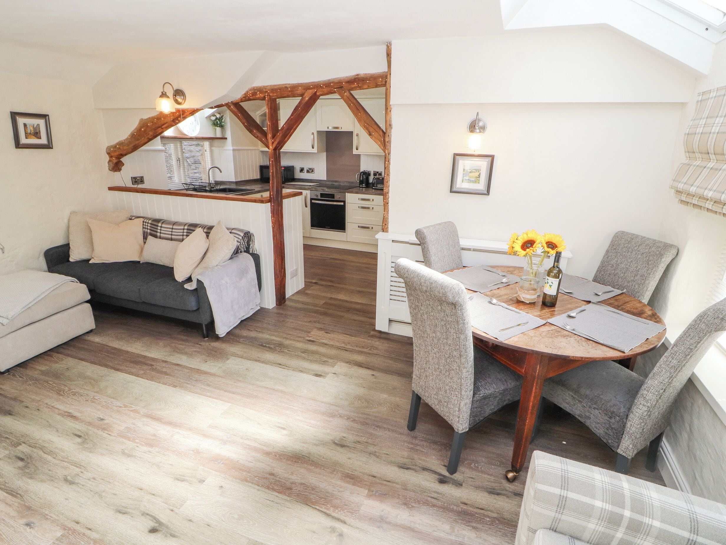 Ein gemütliches Wohnzimmer mit einer Couch, einem Esstisch mit Stühlen und einer Küche im Hintergrund.
