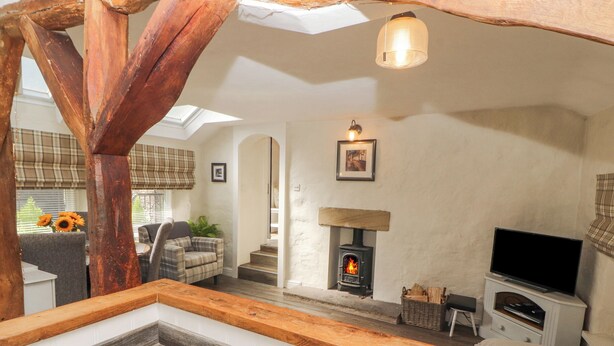 A cozy living room with a fireplace, a television, and a dining area with a table and chairs. - The Landings (Carnforth)