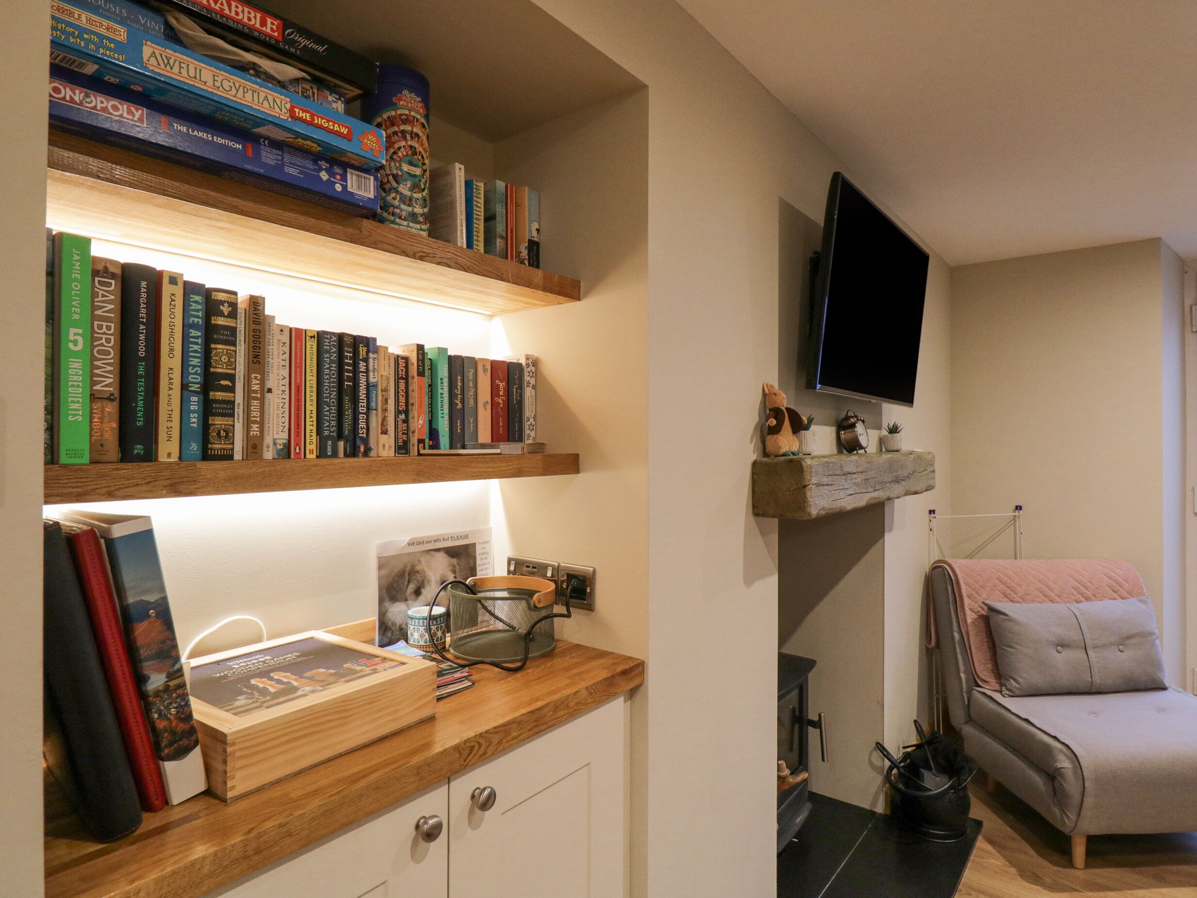 Un accogliente soggiorno con una libreria, un televisore a parete e un divano confortevole.