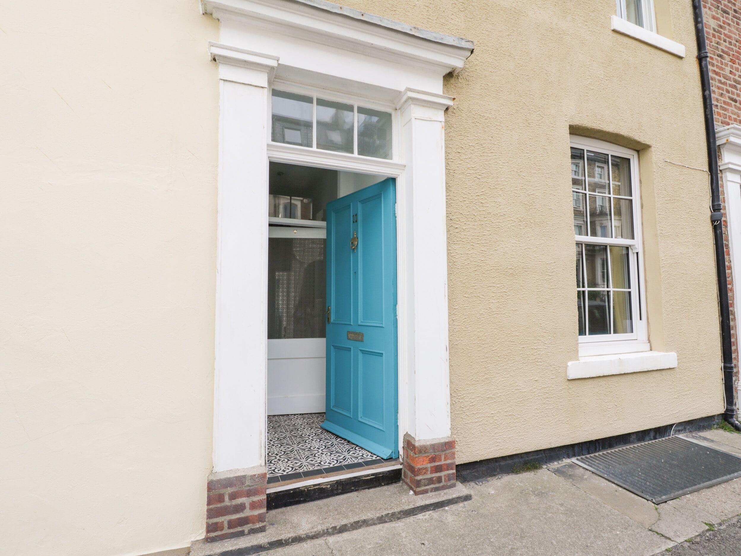 Une maison avec une porte bleue, une petite fenêtre et un chambranle de porte blanc.