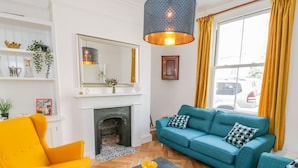 A living room with a fireplace, a sofa set, a yellow armchair, and a black coffee table. - West Cliff House (Whitby)