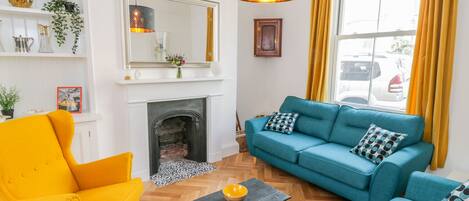 A living room with a fireplace, a sofa set, a yellow armchair, and a black coffee table.