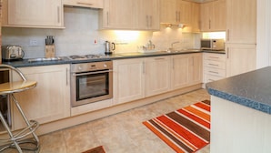 Una cocina moderna con armarios de madera clara, electrodomésticos de acero inoxidable y un tapete a rayas.