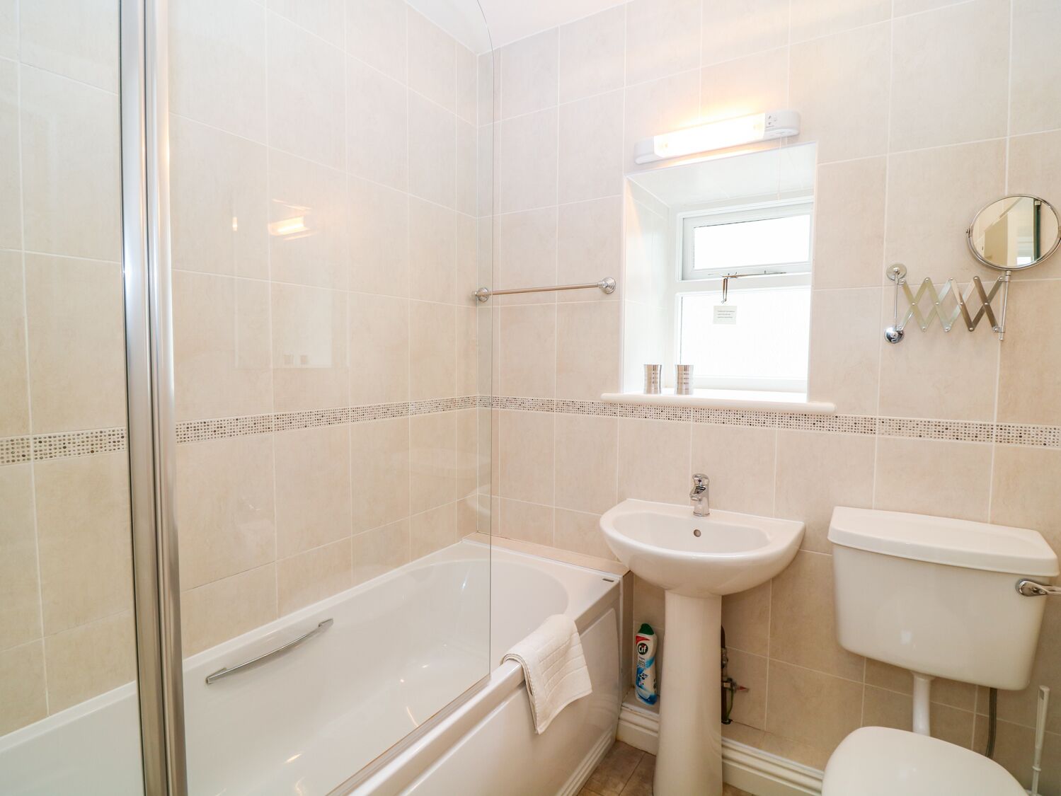Une salle de bain avec une douche à parois de verre, un lavabo sur colonne et des toilettes.