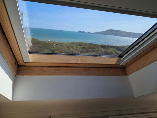 A skylight with a view of a body of water and hills. - The Lookout -the House With A View (Weymouth)