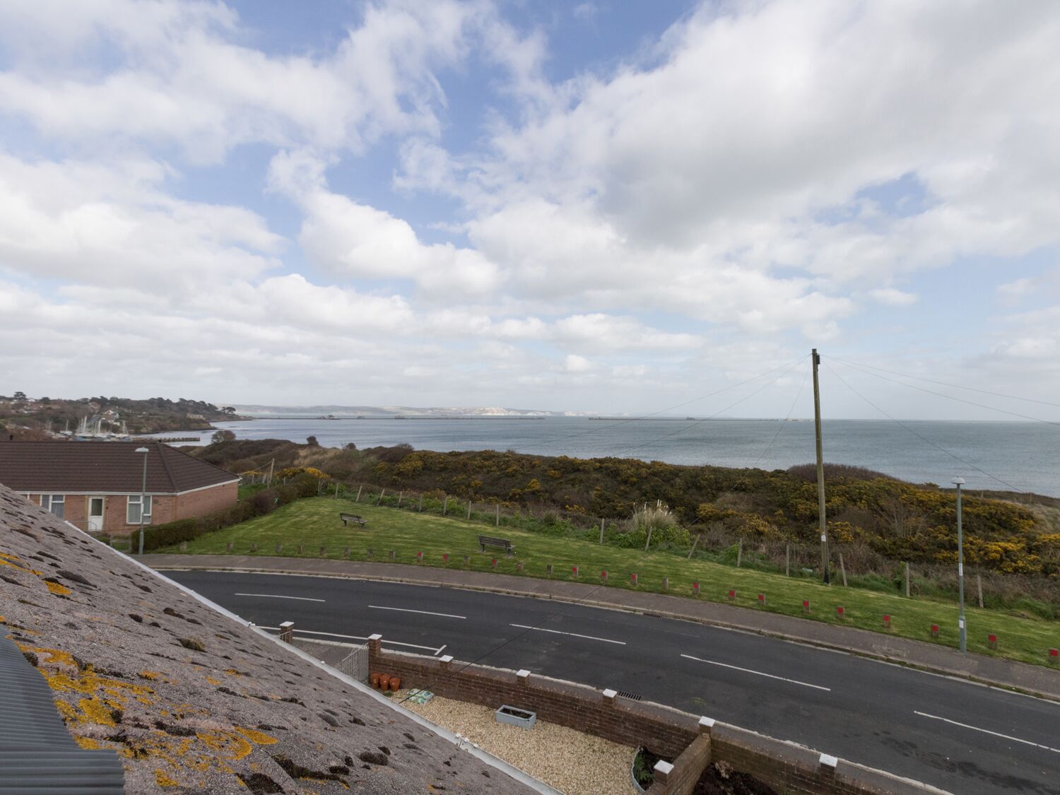 A coastal road with a grassy area and a building on the left.