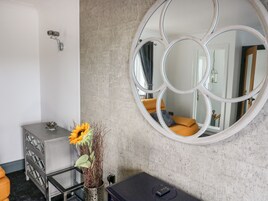 Uma casa de banho moderna com um espelho grande, um vaso com girassóis, um armário cinzento e uma mesa de massagem preta.