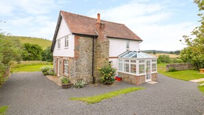 A house with a stone and white exterior, a tiled roof, and a conservatory.