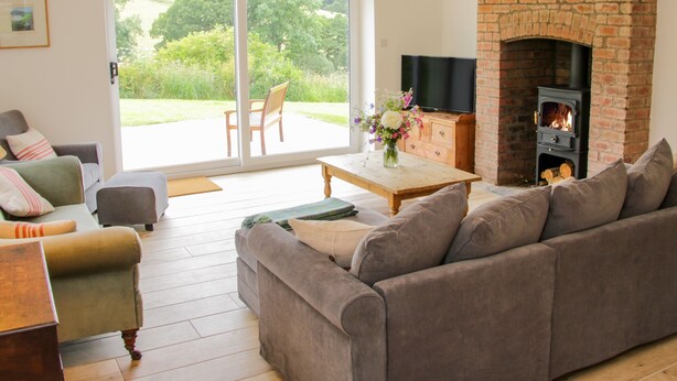 A living room with a sofa, armchairs, a coffee table, a fireplace, and a TV.