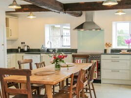 Una cocina con una mesa de madera, sillas, estufa y ventana.