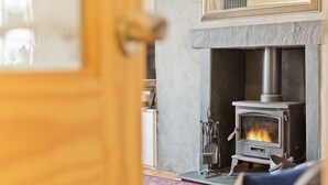 A room with a stone fireplace, a mirror above it, and a door leading to another area. - Harley House (Broughton in Furness)