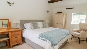 A bedroom with a bed, bedside table, chair, wardrobe, and a window. - Croft Cottage (Skipton)