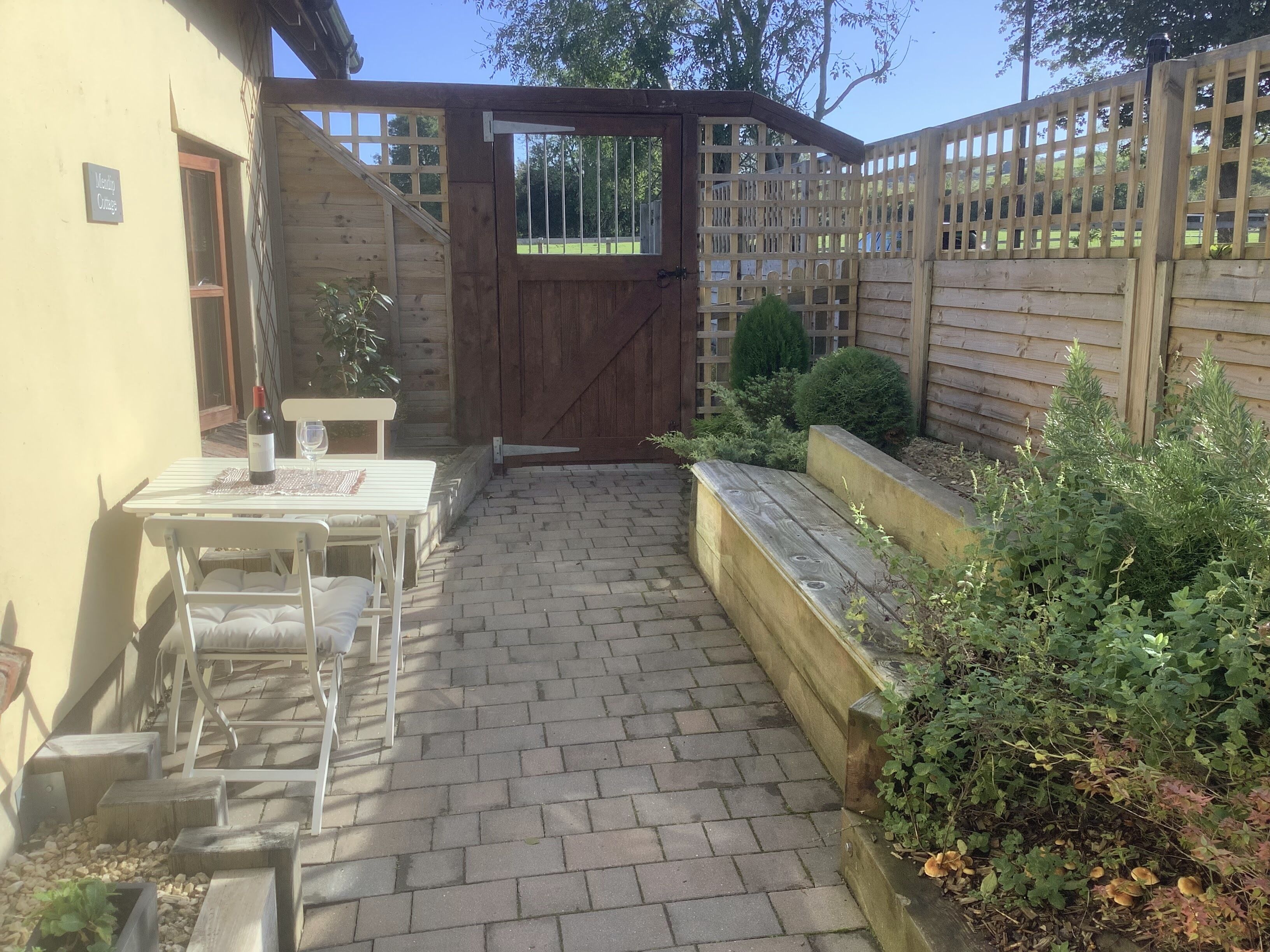 Un patio con mesa y sillas, un portón de madera y una cerca de madera.