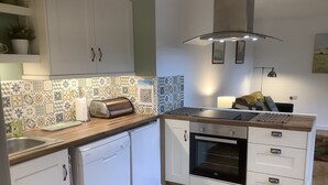 Eine kleine Küche mit weißen Schränken, einem eingebauten Backofen, einem Toaster und einer Holz Arbeitsplatte.
