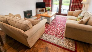 A living room with a sofa, a wooden coffee table, a television, and a fireplace. - Potters Barn (Kilgetty)