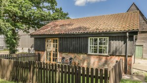 A rustic building with a tiled roof, a wooden door, and a picket fence. - The Bull Pen (Eye)