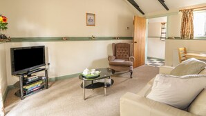 A living room with a television, a chair, a table with a teapot, and a sofa. - The Bull Pen (Eye)