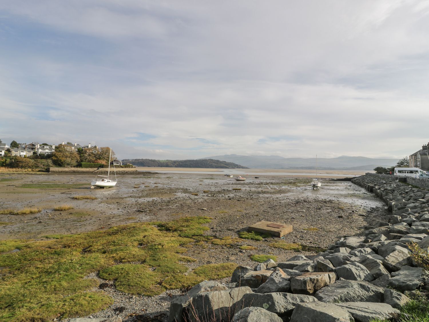 A coastal landscape with a rocky shoreline, a white boat, and houses in the background.