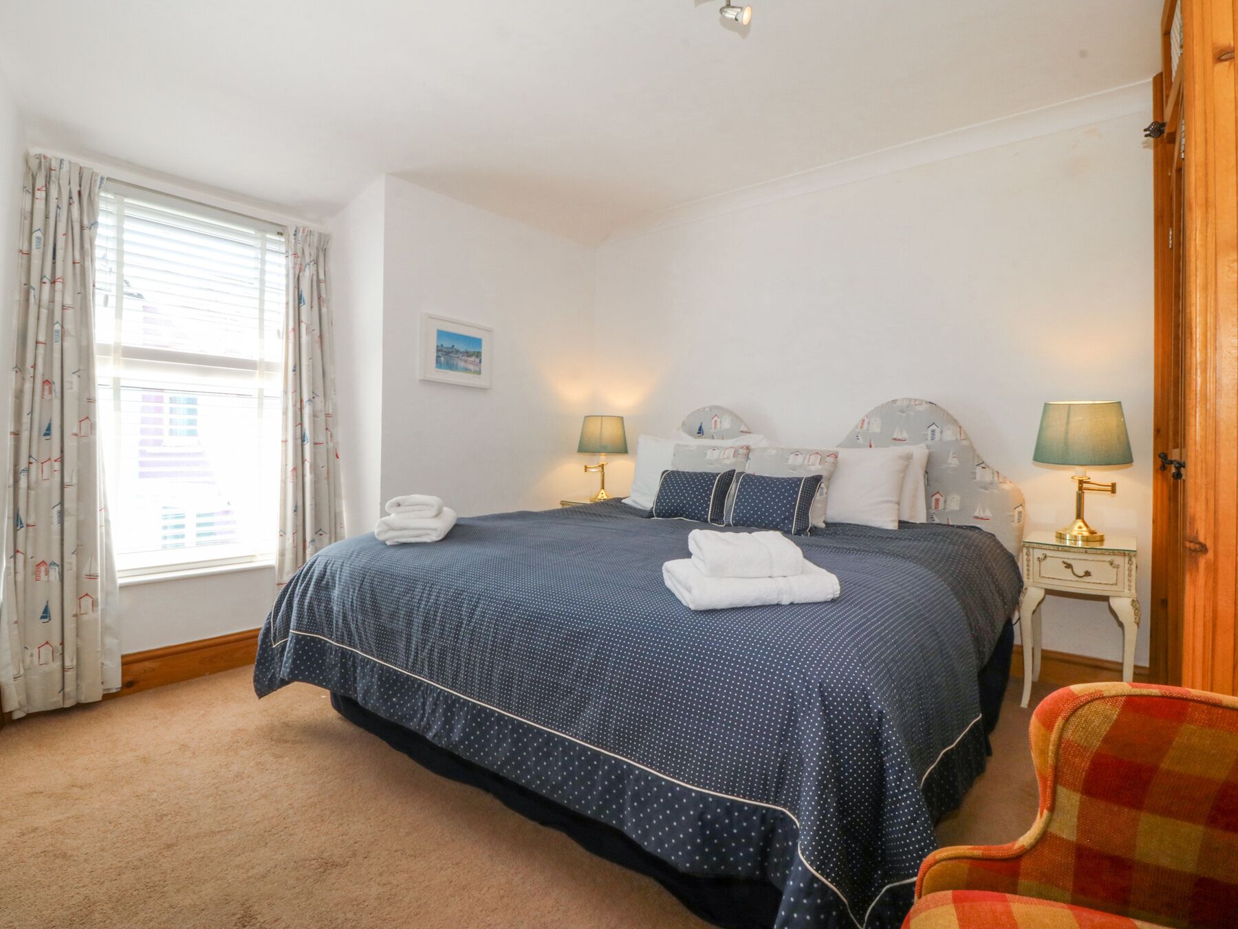 A neatly arranged bedroom with a large bed, two bedside lamps, and a chair.