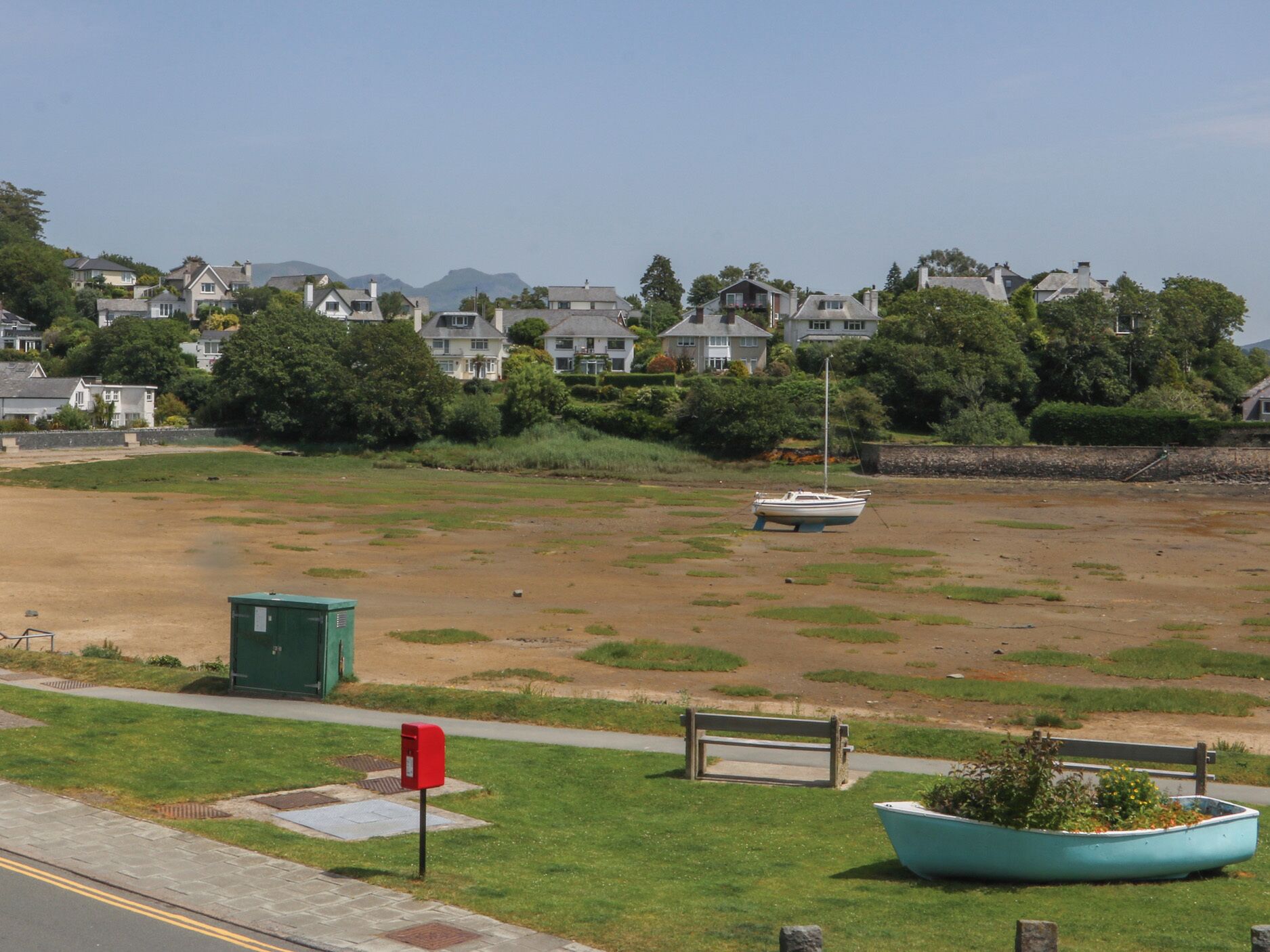 A coastal area with a sandy beach, a row of houses, and a boat in the water.