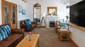 A living room with a fireplace, a television, a sofa, and a coffee table. - Bay View Apartment (Porthmadog)