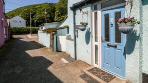 A narrow street with a blue door and hanging flower baskets. - Bay View Apartment (Porthmadog)