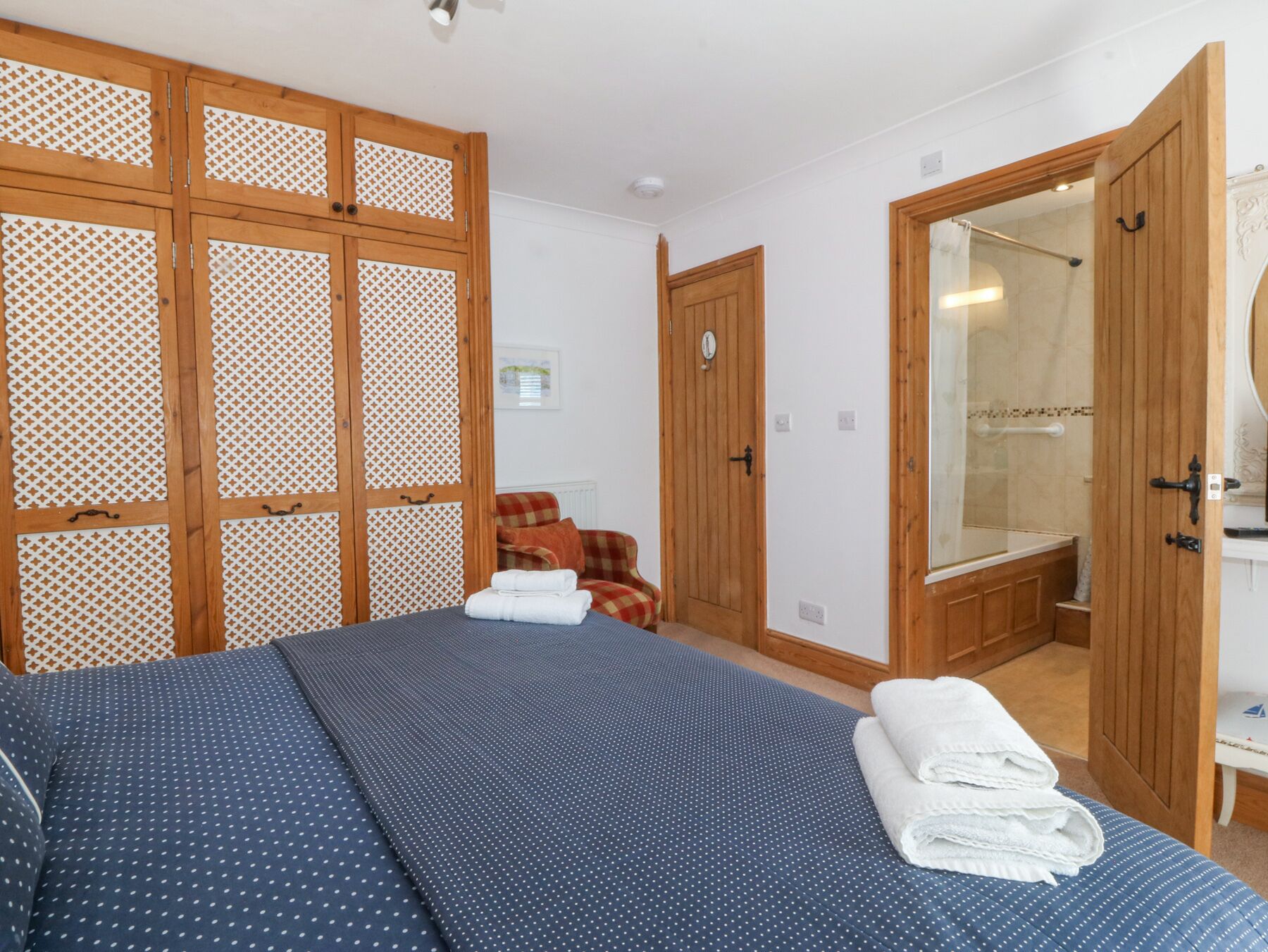 Quarto com cama, guarda-roupa de madeira, banheiro com espelho e chuveiro.