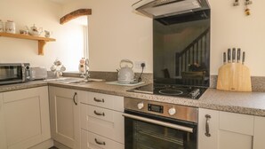 A modern kitchen with a microwave, toaster, kettle, sink, and oven. - The Barn (Workington)