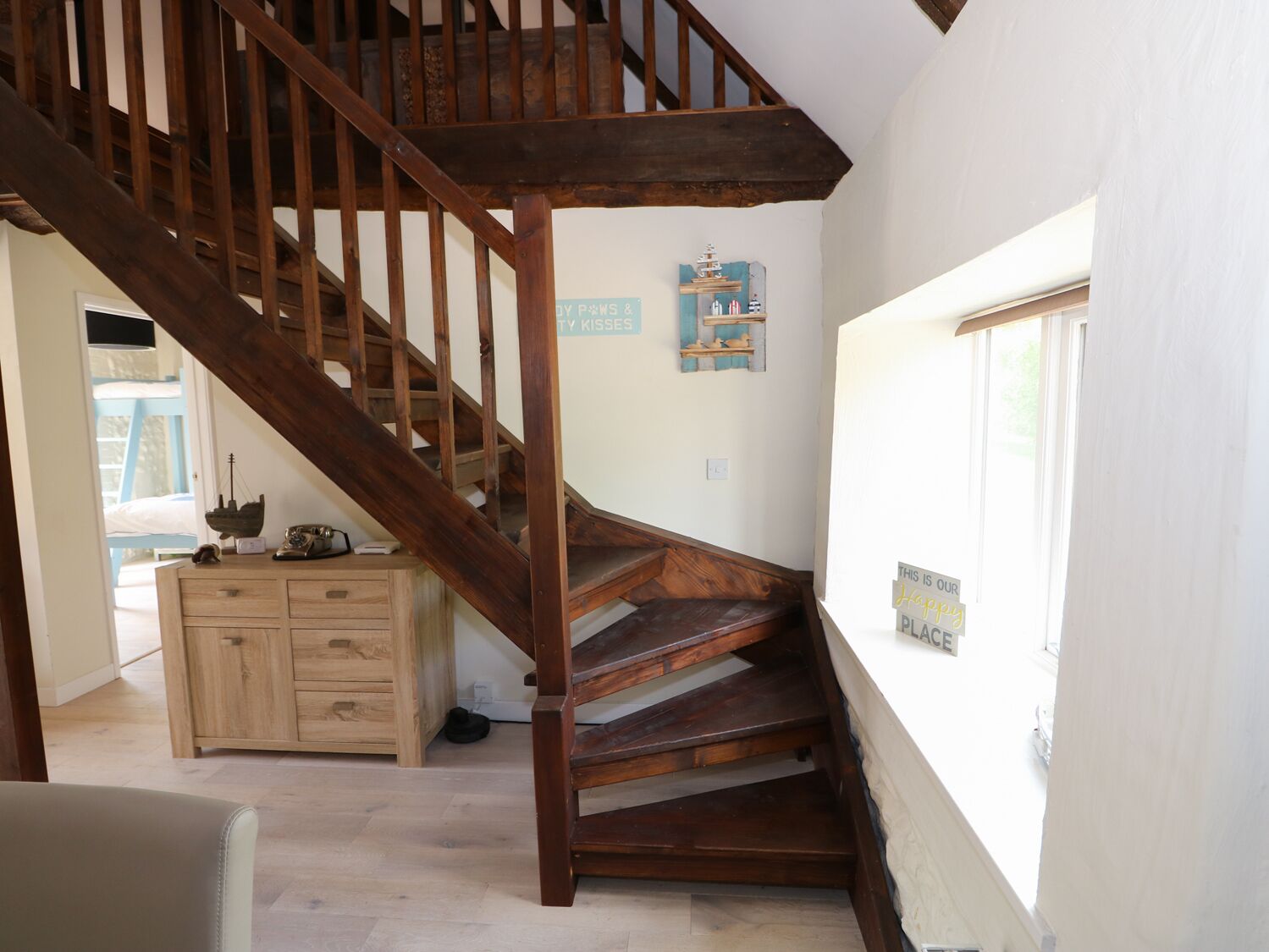 Eine Holztreppe führt zu einer zweiten Etage, ein Holzschrank und ein Fenster mit Blick.